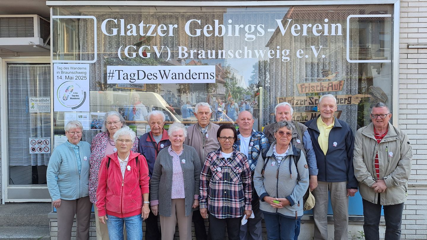 Menschen unterschliedlichen Alters stehen im Freien vor einem Schaufenster.