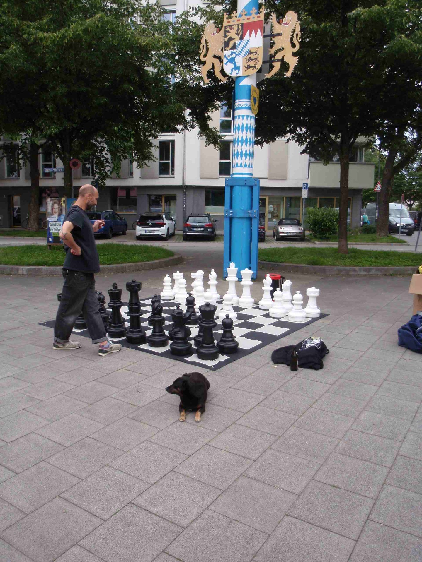 Ein Mann steht vor dem Freiluftschach am Hans-Mielich-Platz und überlegt den nächsten Zug