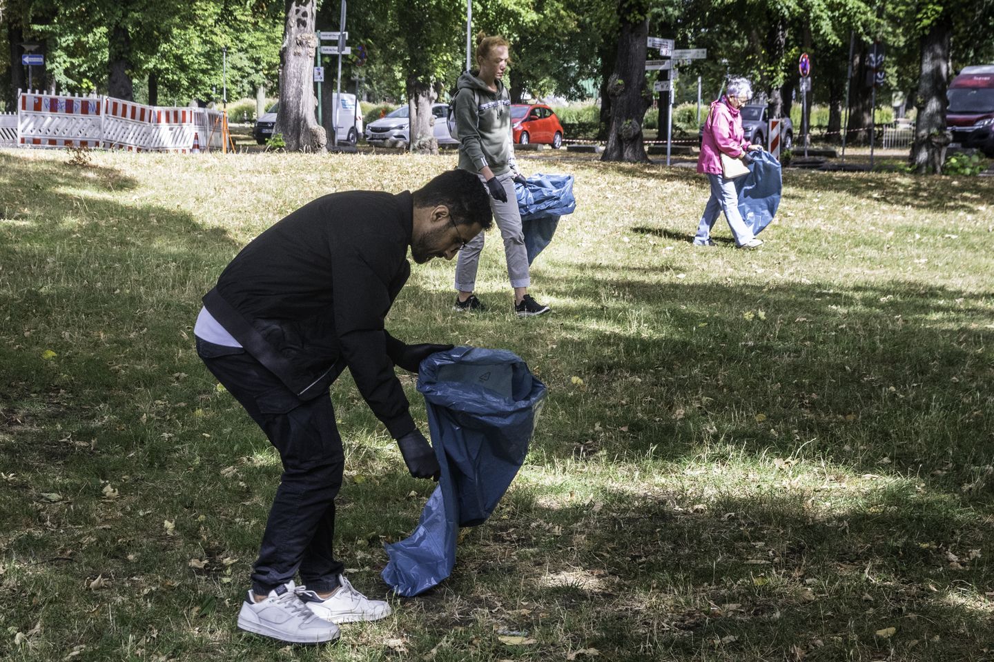 Mehrere Personen sammlen in einem Park Müll.