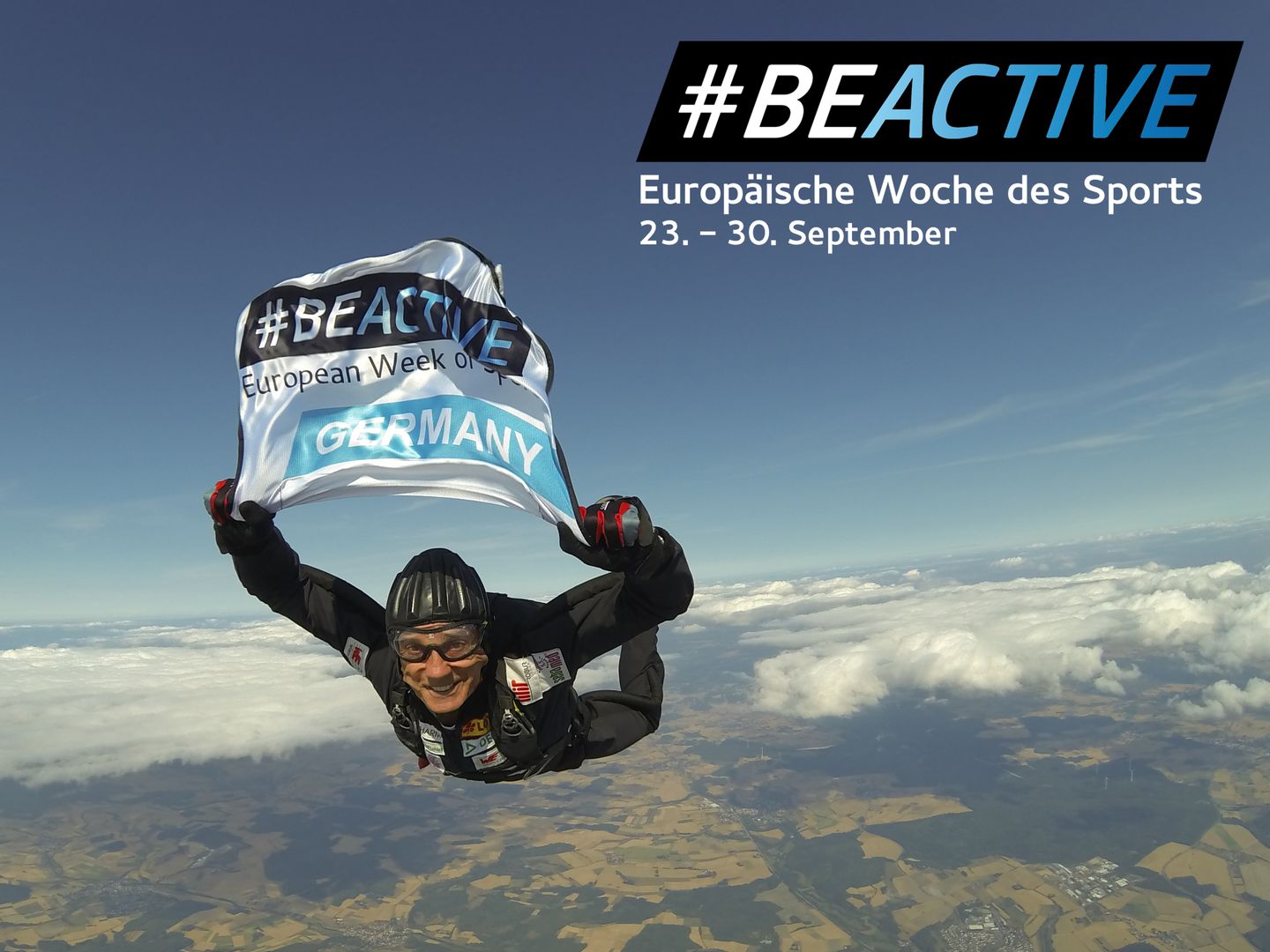 Eberhard Gienger hält eine #BEACTIVE Flagge in der Hand.  Oben rechts im Bild ist das Logo von #BEACTIVE. Darunter steht in weißer Schrift "Europäische Woche des Sports 23.-30. September