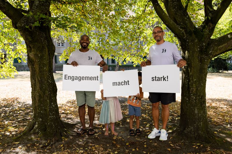 Eine Gruppe von Personen steht in Reihen und hält Buchstaben hoch. Die Buchstaben ergeben zusammen den Kampagnen-Slogan “Engagement macht stark!”.