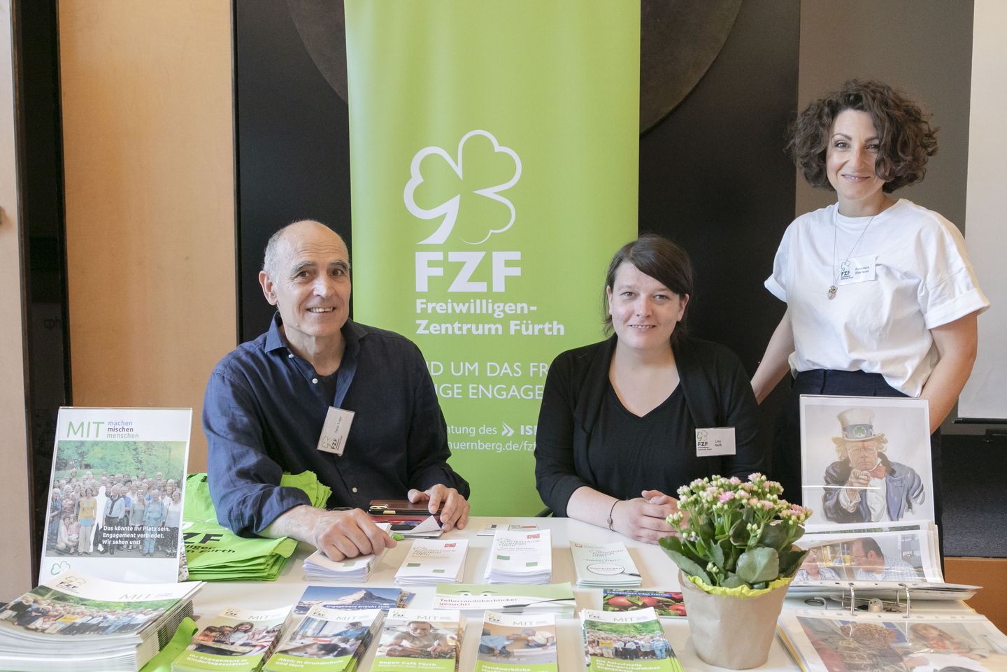 Drei Mitarbeiter/innen der FZF stehen am Infostand bereit, Interessierte über die Möglichkeit zu beraten, in Fürth ehrenamtlich aktiv zu werden.