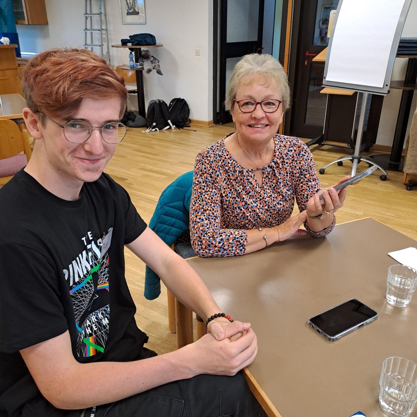 Auf dem Bild ist eine jüngere und ältere Person zu sehen. Beide lachen freundlich.