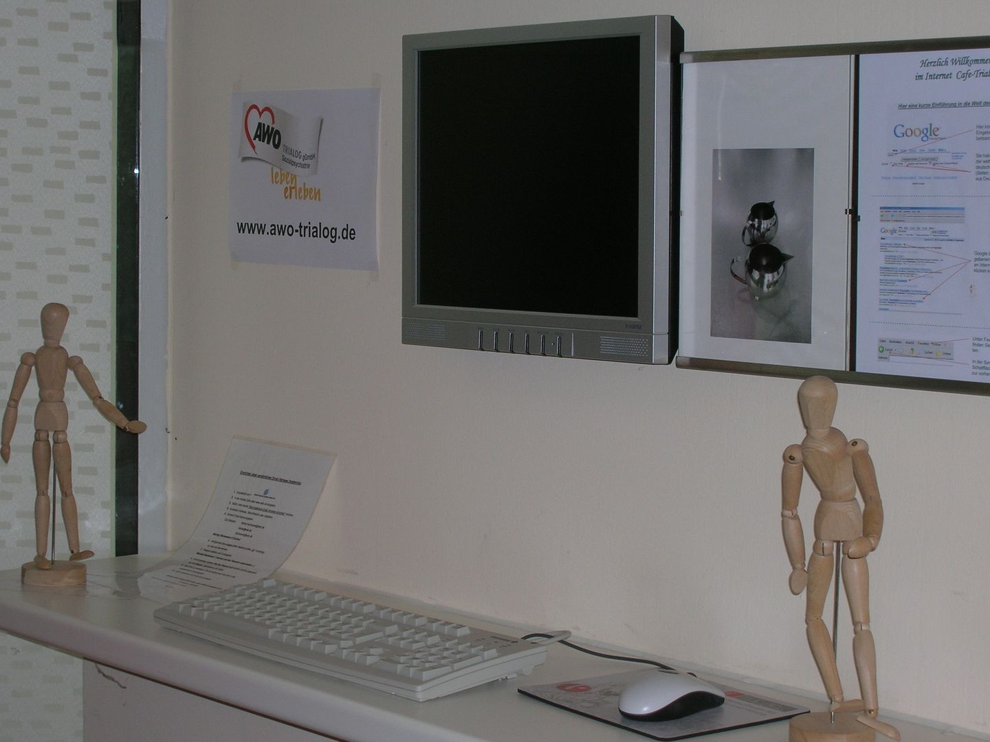 zu sehen sind die Computer des Internet Cafes, sowie die Internetadresse und hölzerne Marionettenpuppen