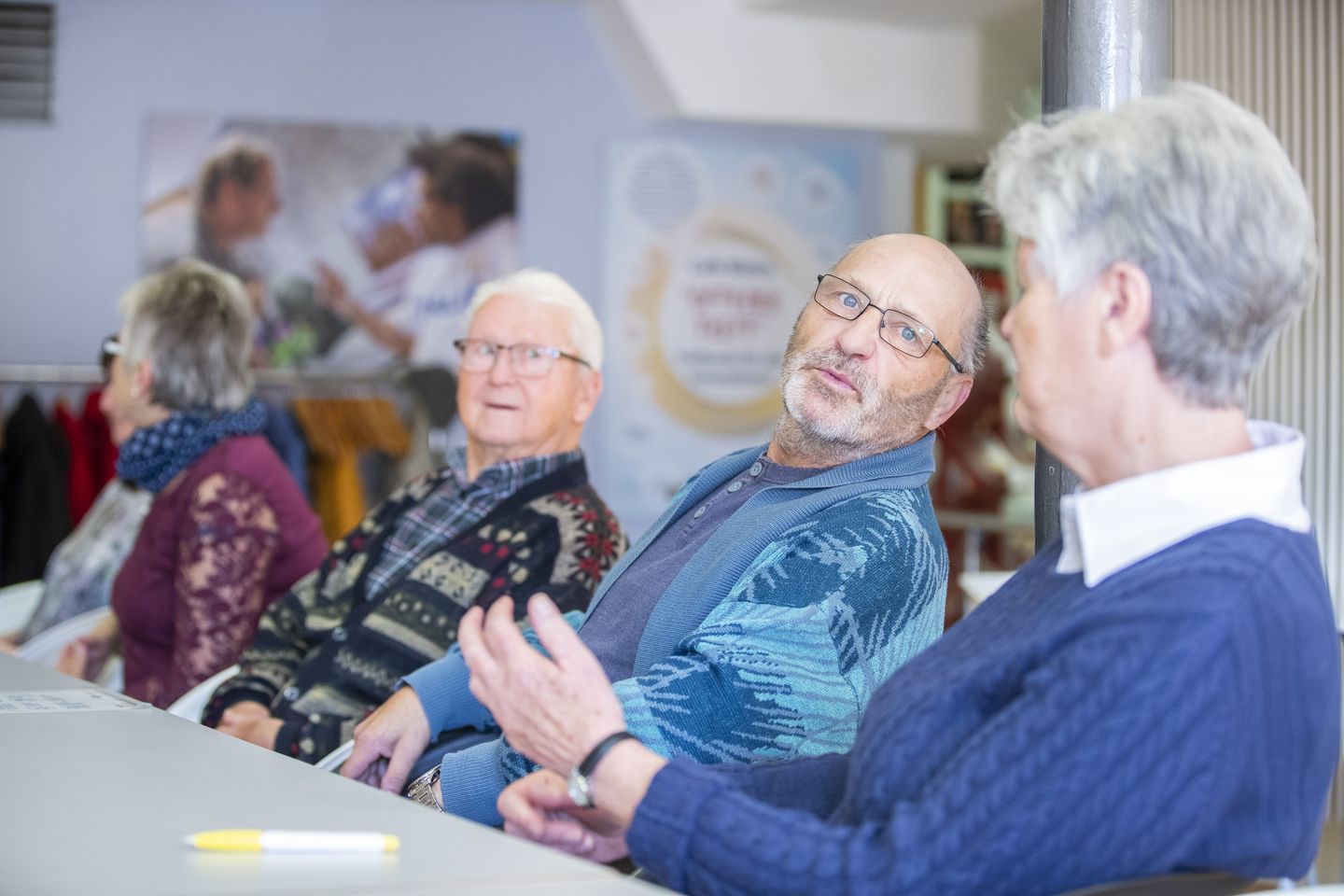 Mehrere Senior*innen sitzen an einem Tisch, unterhalten sich und lachen