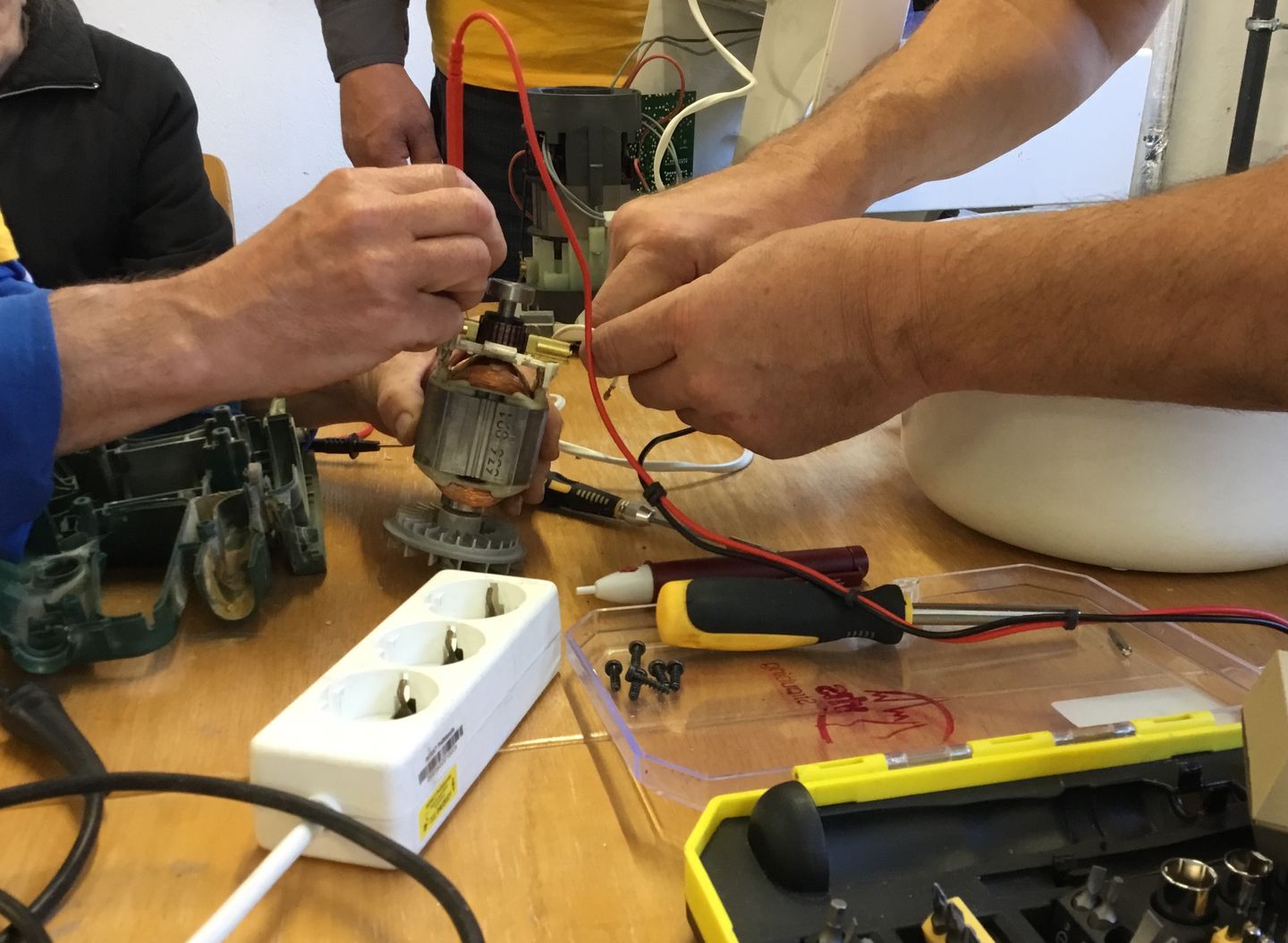 Hände, die Elektrogeräte reparieren.