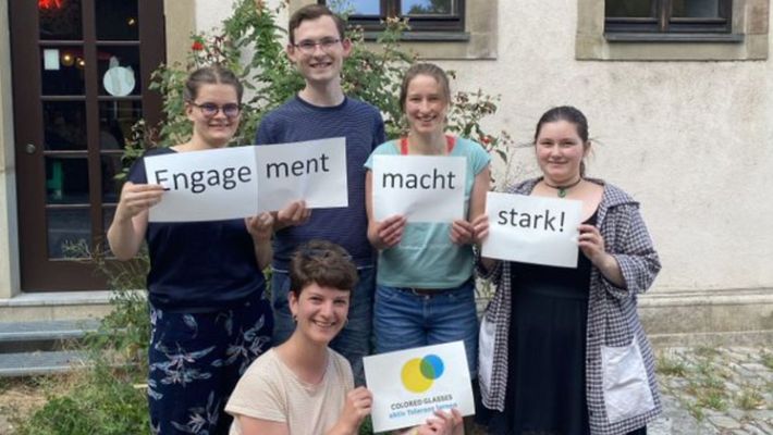 Eine Gruppe von Personen steht in Reihen und hält Buchstaben hoch. Die Buchstaben ergeben zusammen den Kampagnen-Slogan “Engagement macht stark!”.