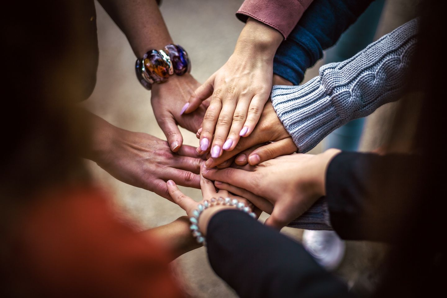 Menschen legen ihre Hände aufeinander und symbolisieren so das kooperative Miteinander
