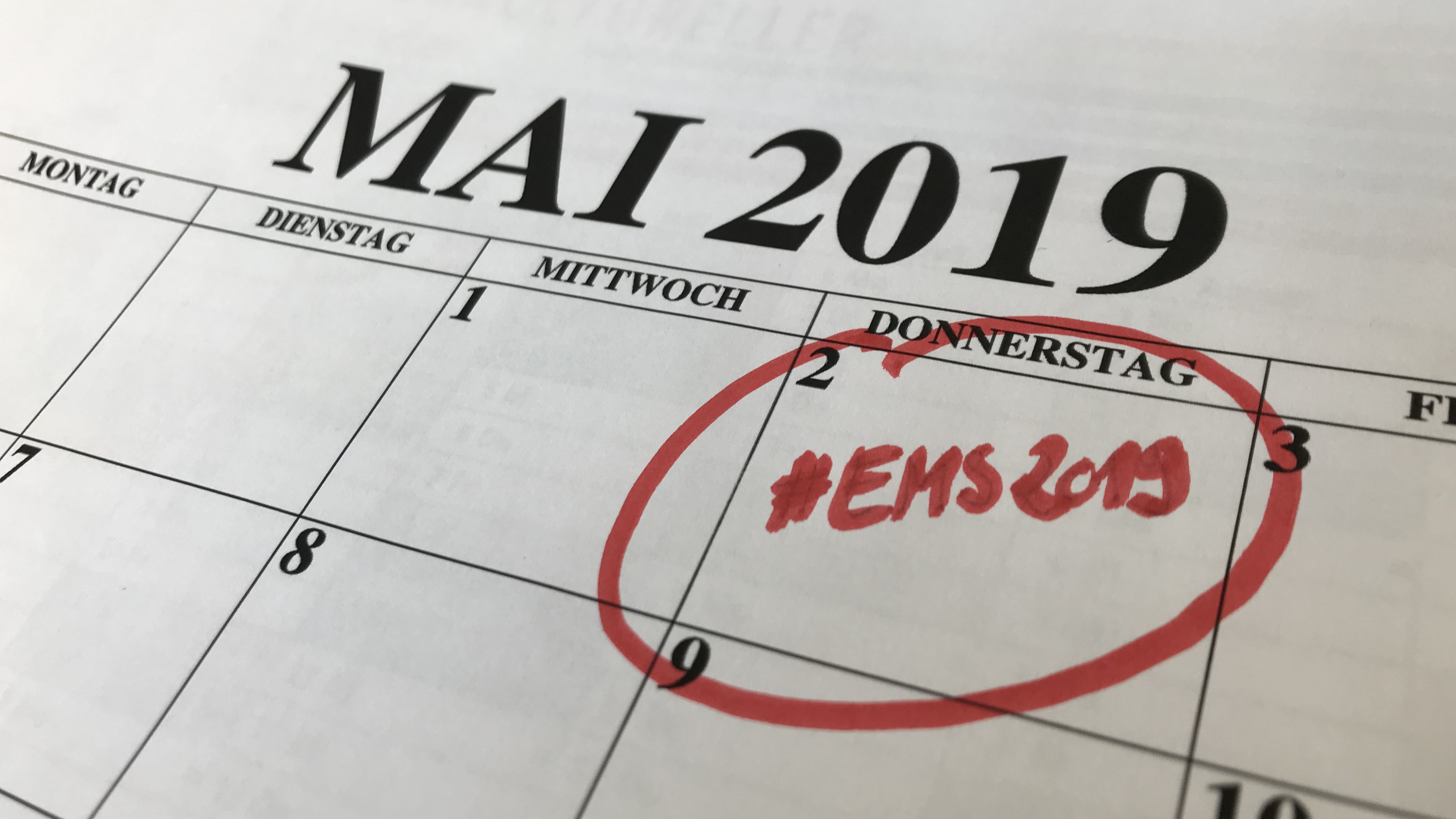 Abgebildet ist ein Kalenderblatt Mai 2019. Der 2. Mai ist rot umrandet und mit dem Hashtag EMS2019 beschrieben.