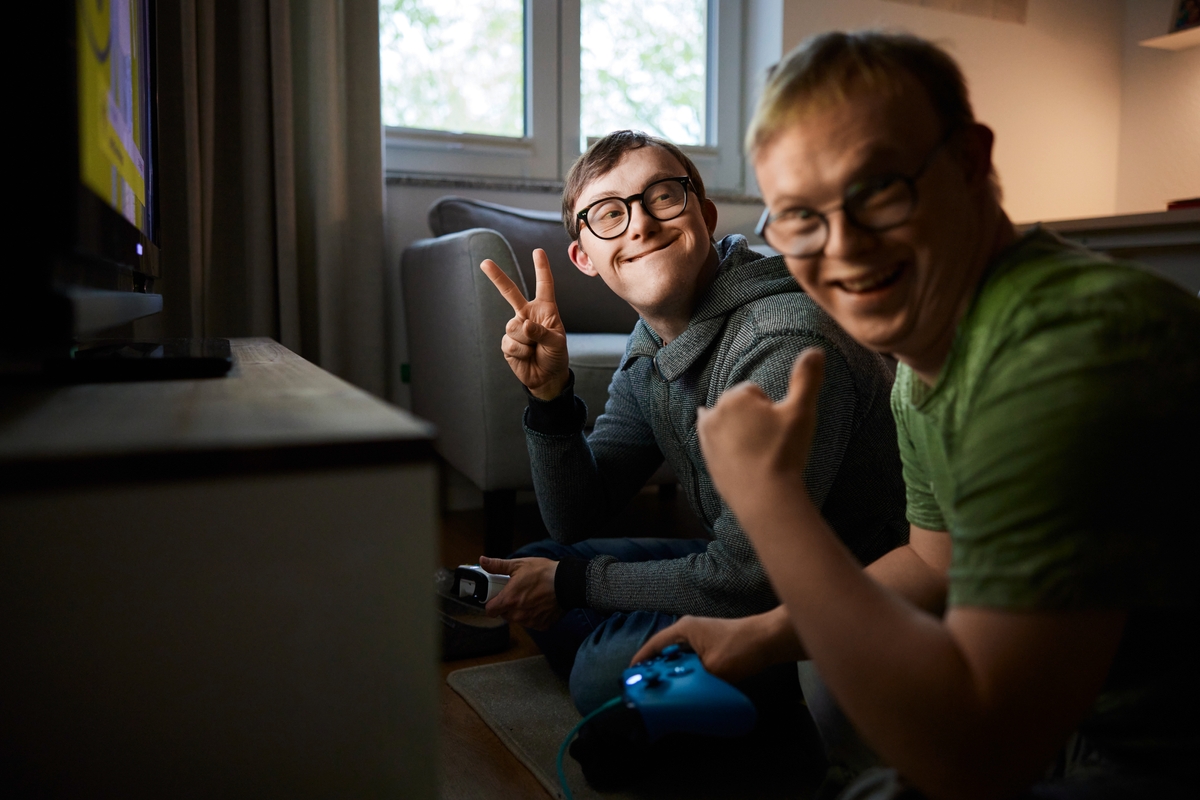 Zwei junge Männer schauen in die Kamera und laden zum mitmachen ein