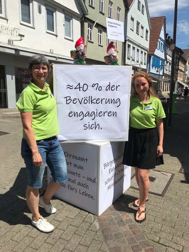 Die beiden hauptamtlichen Angestellte stehen an ihrem Infostand